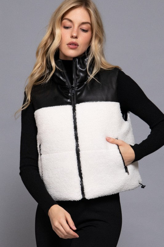 Woman wearing a black and white quilted vest against a gray background