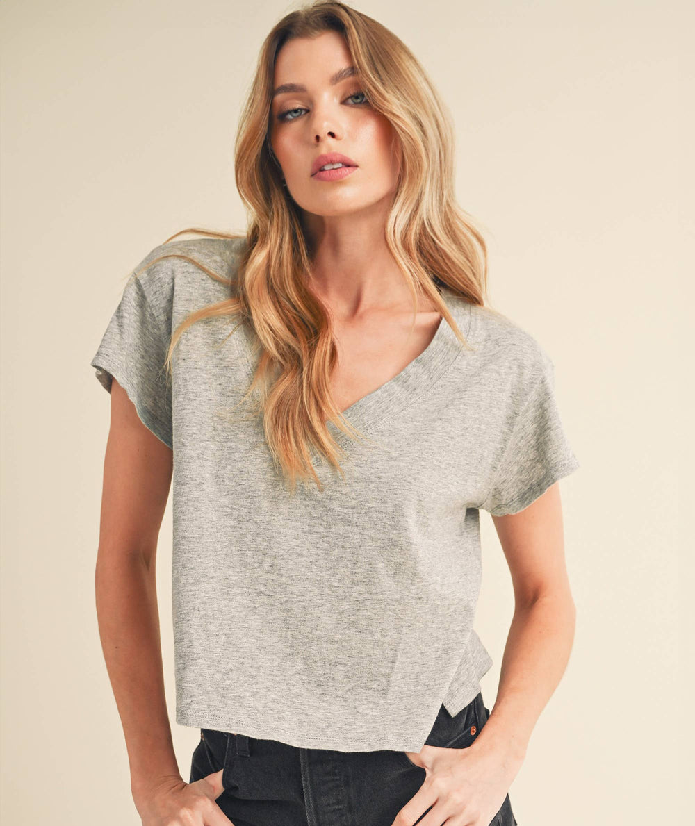 Woman wearing a gray top and black shorts on a beige background