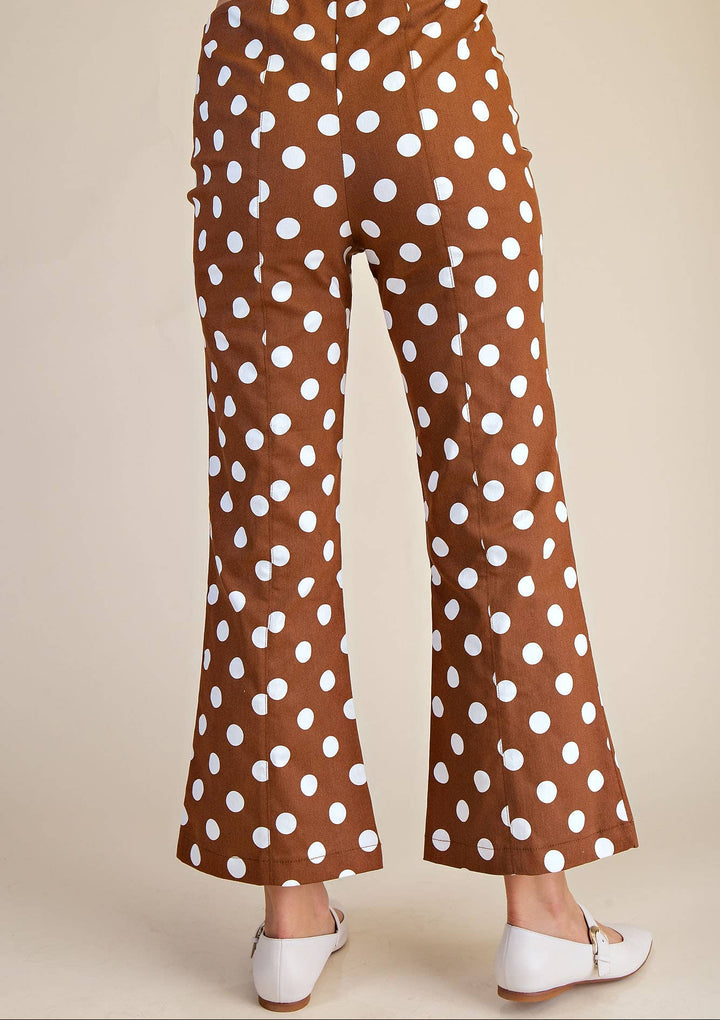 Brown pants with white polka dots worn by a person on a beige background