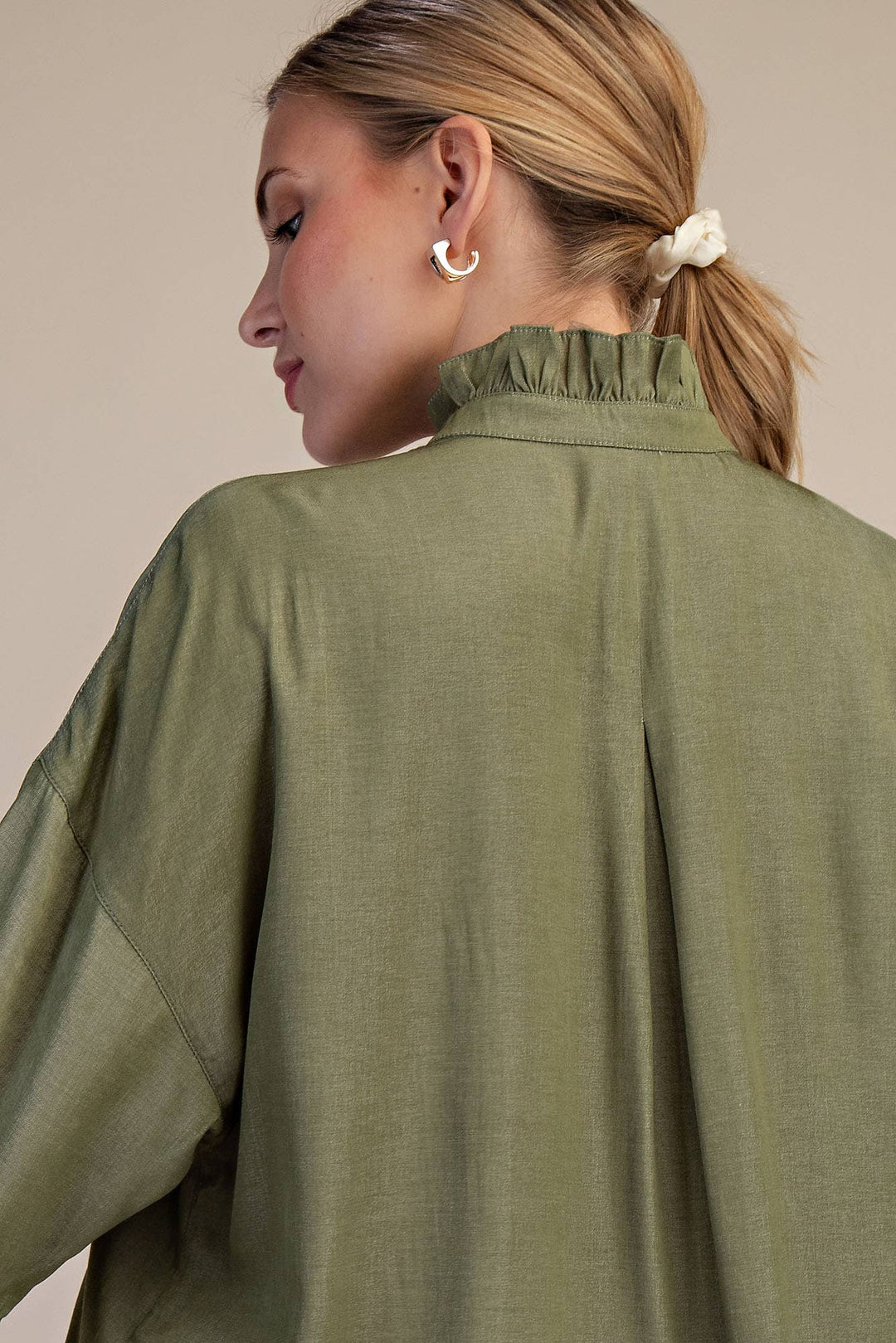 Person wearing a green jacket with a neutral background