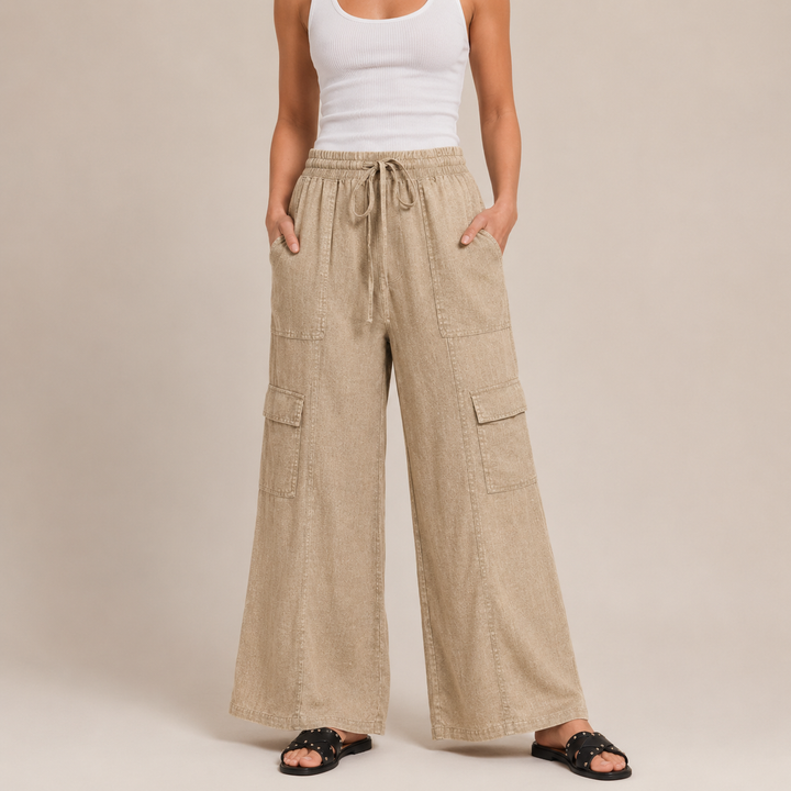 Person wearing beige cargo pants and a white tank top on a plain background