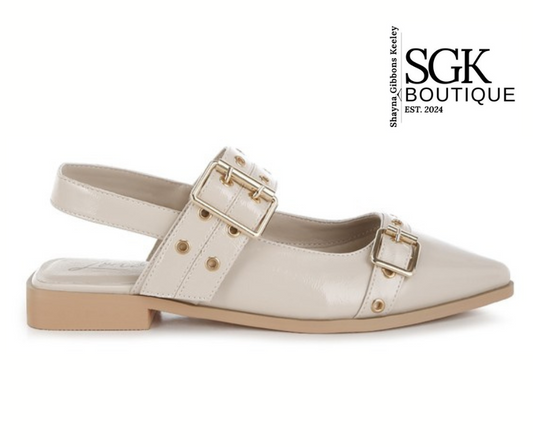 Beige flat shoe with gold buckles on a white background, featuring SGK Boutique logo.