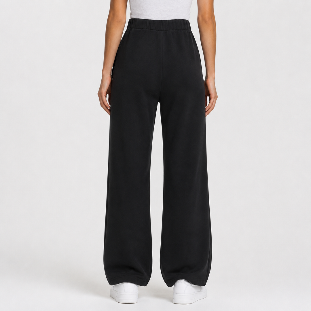 Black wide-leg sweatpants shown on a model from the back, paired with a white top and white sneakers against a light gray studio background.