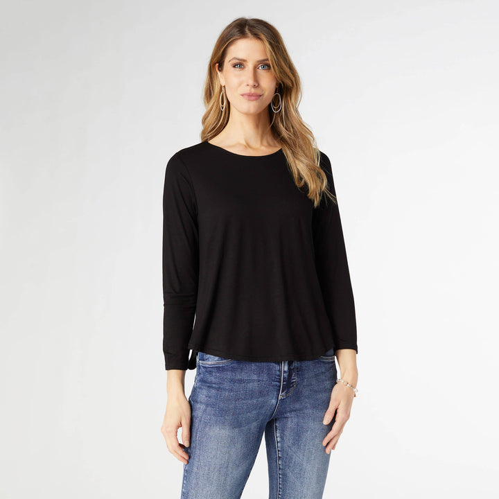 Woman wearing a black long-sleeve top and blue jeans on a white background