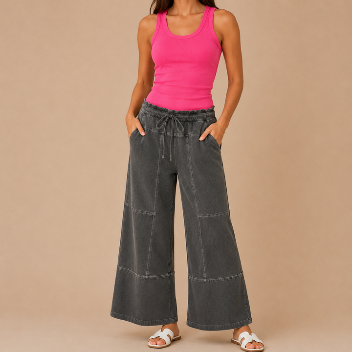 Person wearing a pink tank top and black wide-leg pants on a beige background