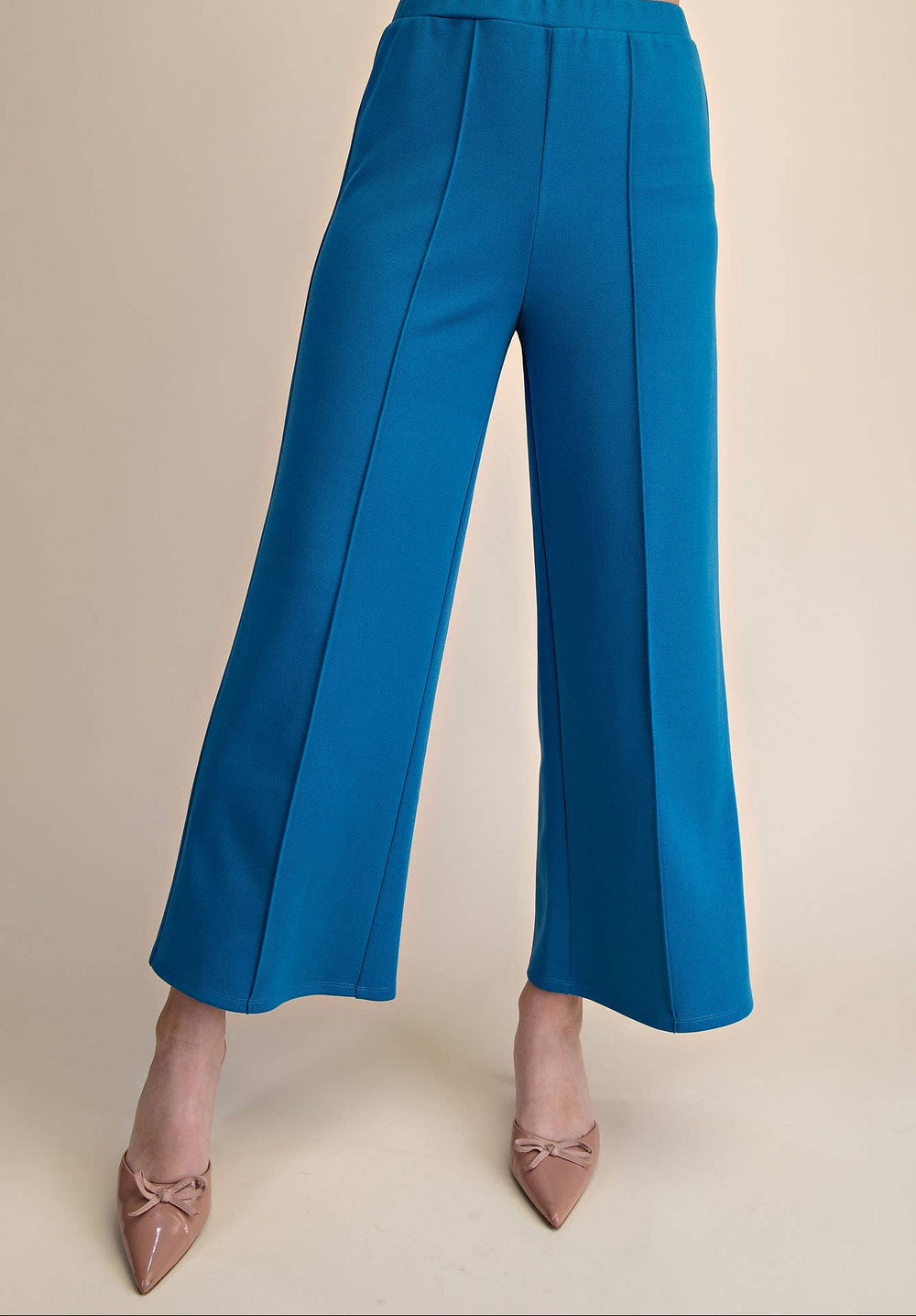 Blue wide-leg pants worn by a person on a beige background