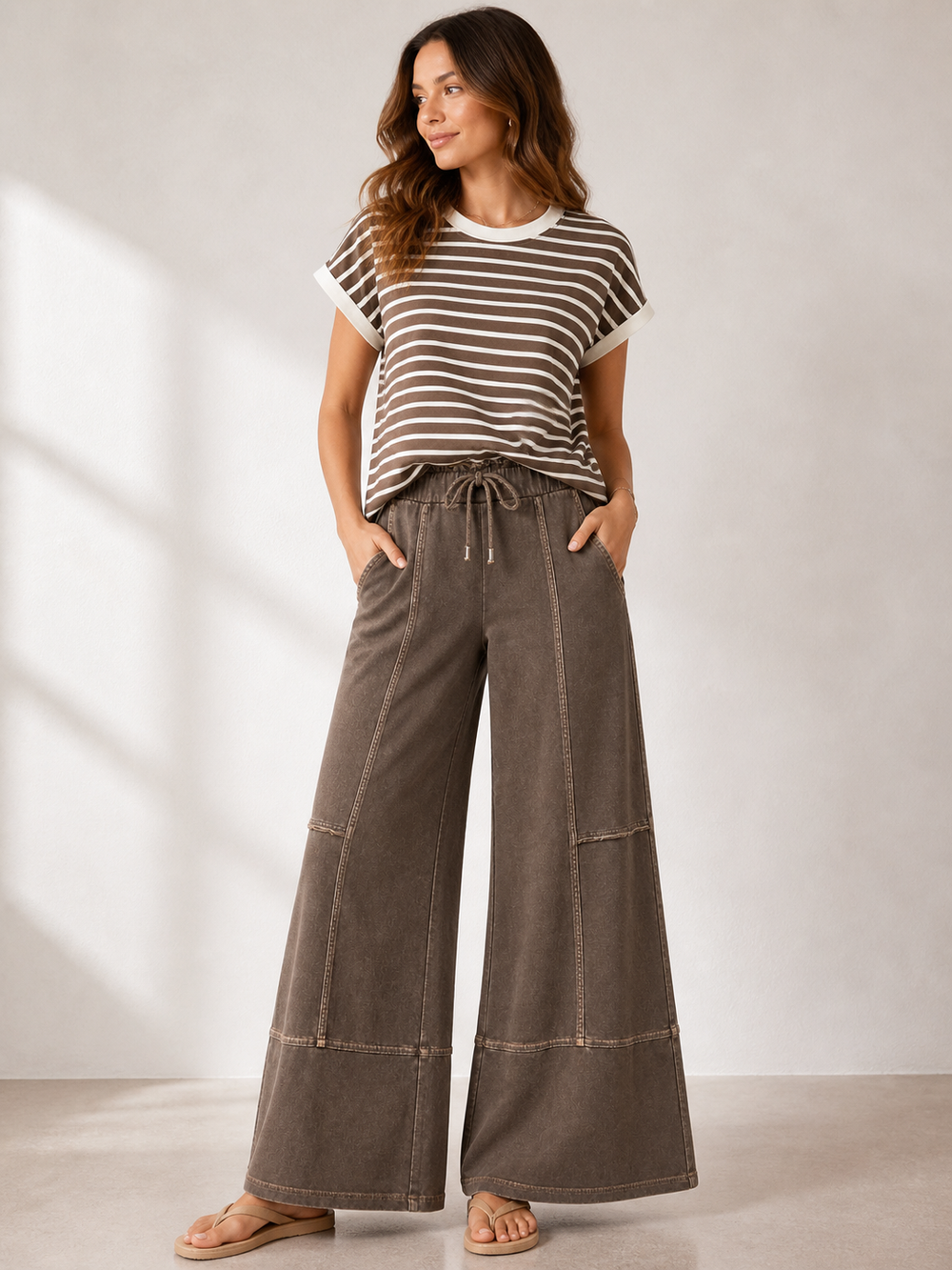 Woman wearing a striped shirt and wide-leg pants against a neutral background