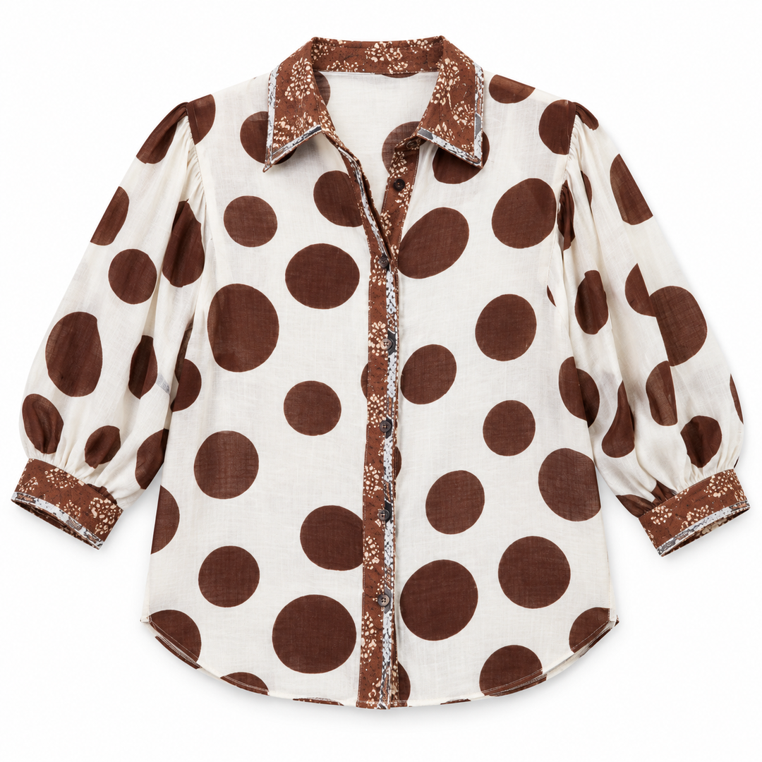 A women's long-sleeve button-up blouse with a brown and cream polka dot pattern, featuring a matching patterned collar, cuffs, and front placket.