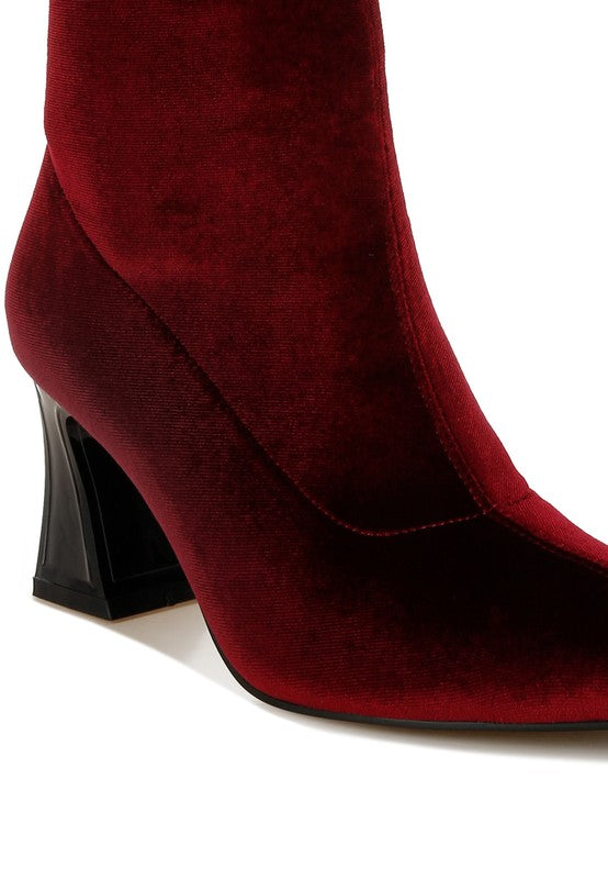 Red suede boot with a black heel on a white background