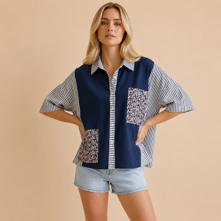 Woman wearing a navy blue and white patterned shirt with denim shorts on a beige background