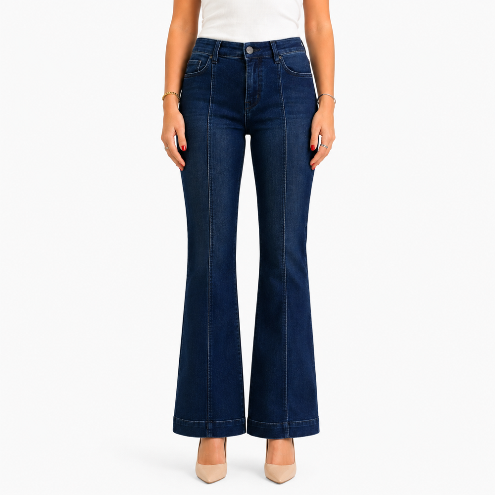 A model wearing dark blue flare jeans, styled with a white top and beige heels, shown from the waist down against a plain white background.