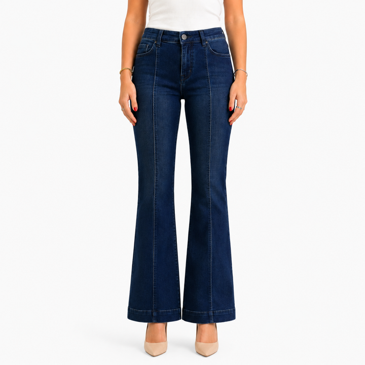 A model wearing dark blue flare jeans, styled with a white top and beige heels, shown from the waist down against a plain white background.