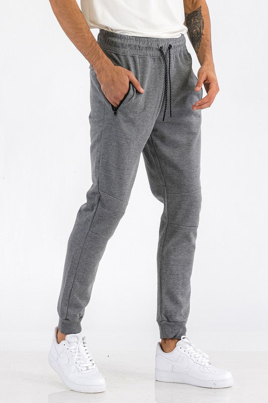 Person wearing gray jogger pants and white sneakers on a white background