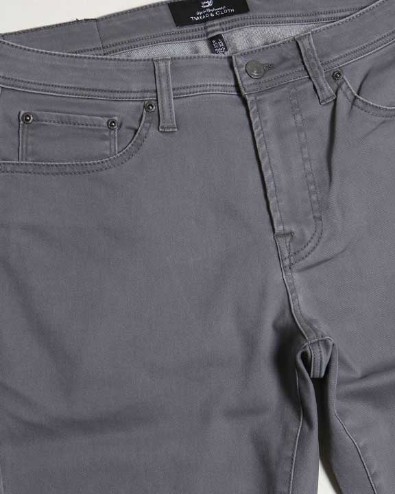 Close-up of gray pants with a brand label on a white background