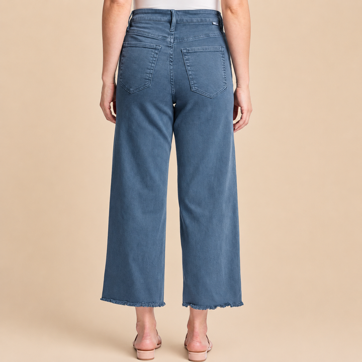 Blue jeans worn by a person on a beige background