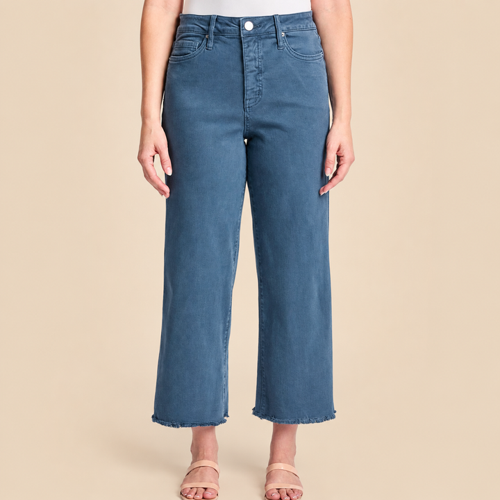 Blue jeans worn by a person on a beige background