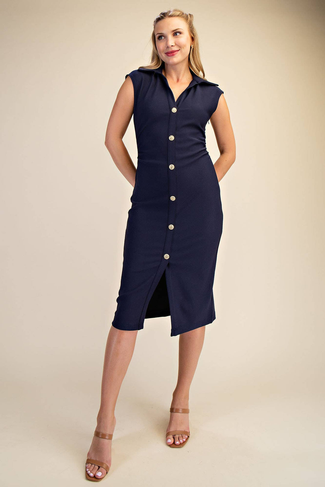 Woman wearing a navy dress with white buttons on a beige background