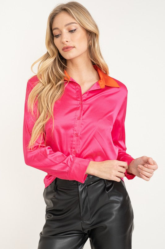 Woman wearing a bright pink shirt with an orange collar on a white background