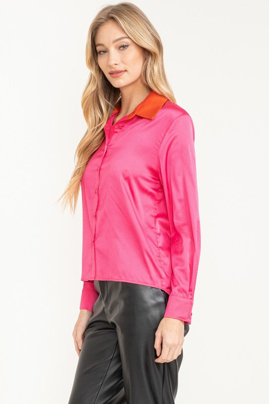 Woman wearing a bright pink shirt with an orange collar on a white background