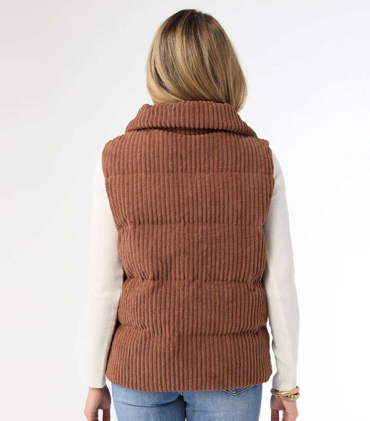 Person wearing a brown quilted vest on a white background