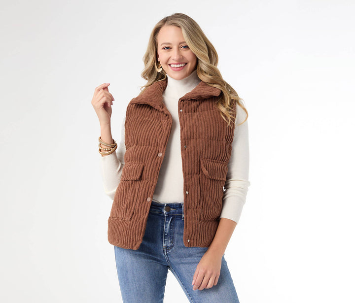 Woman wearing a brown corduroy vest over a white turtleneck and blue jeans on a white background
