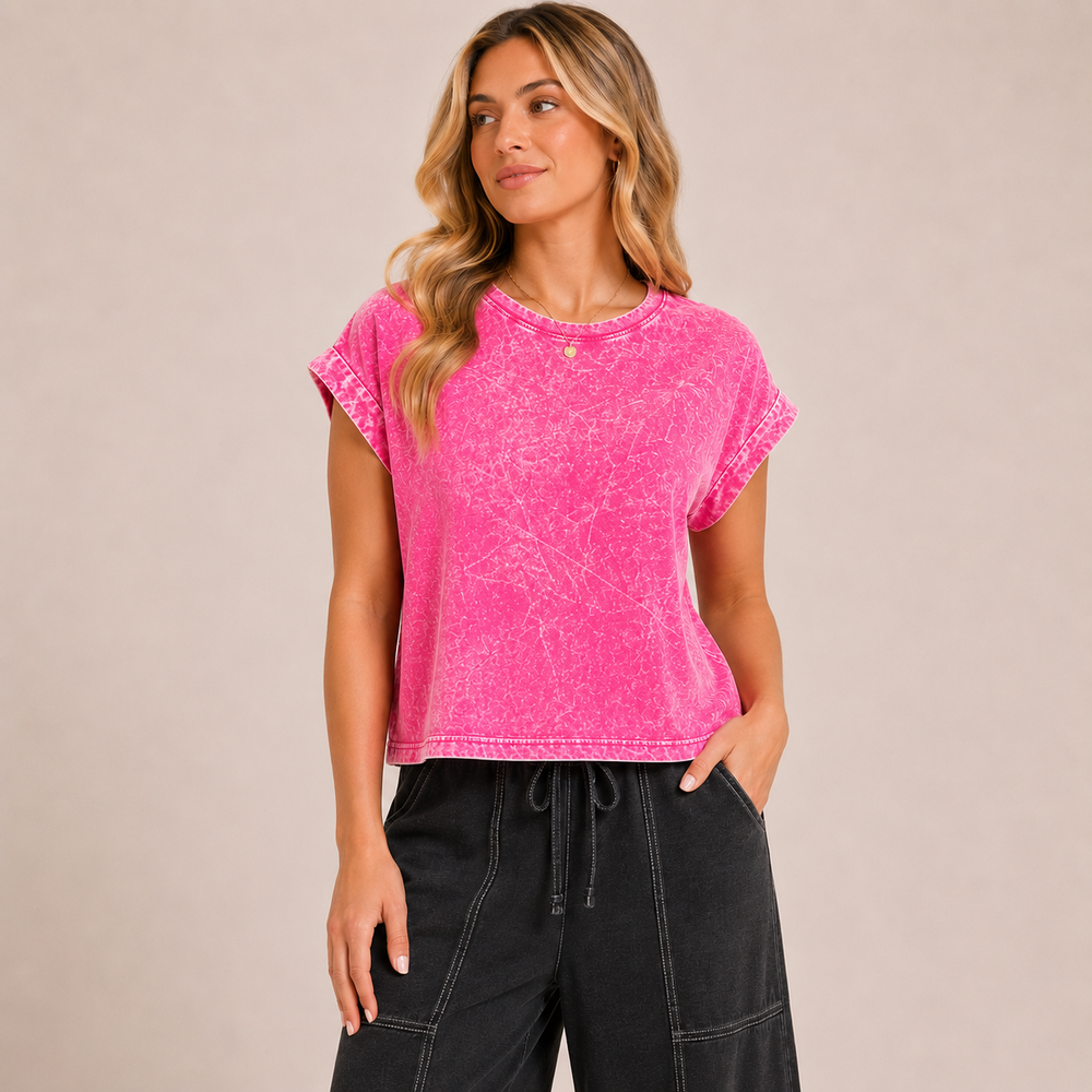 Woman wearing a pink tie-dye shirt and black pants on a beige background