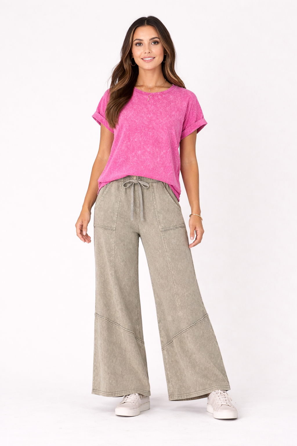 Woman wearing a pink top and beige pants on a white background