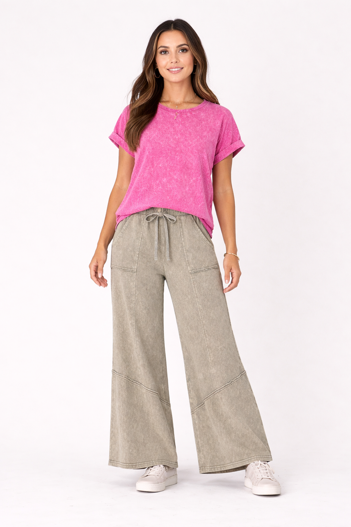 Woman wearing a pink top and beige pants on a white background