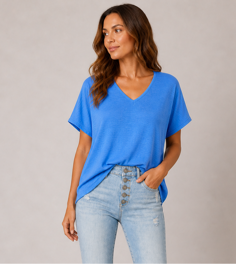 Woman wearing a blue top and light blue jeans against a plain background