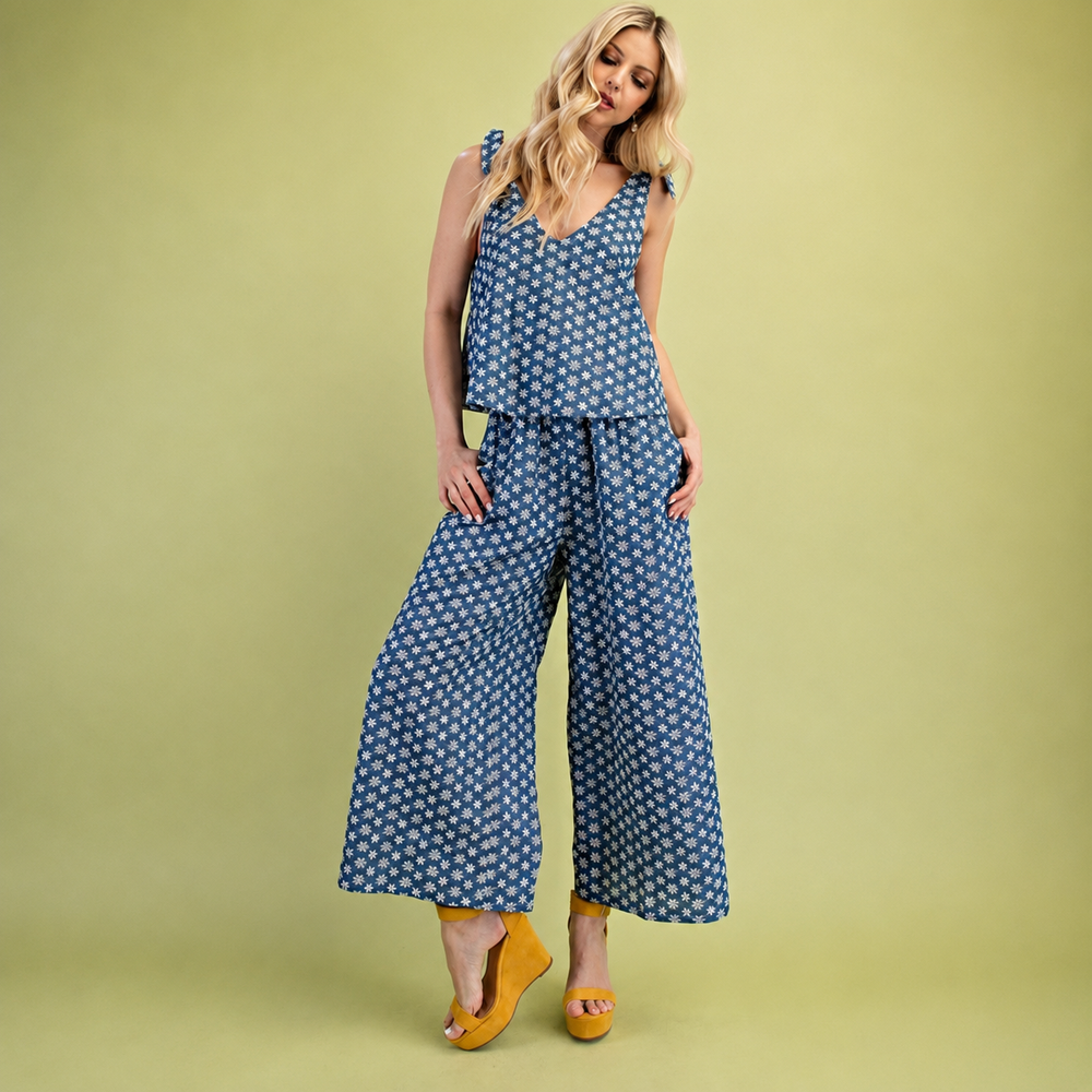 A jumpsuit featuring a sleeveless tie-shoulder straps and wide-leg pants, with small white floral pattern, shown flat on a white background.