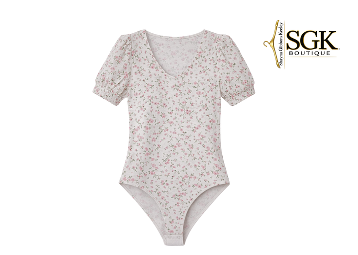 Floral-patterned bodysuit on a white background with SGK Boutique logo.