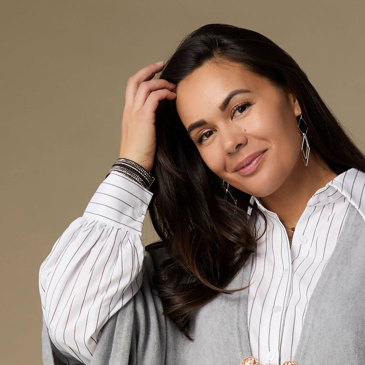 Woman with long dark hair wearing a striped shirt against a beige background