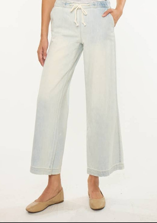 Woman wearing a patterned top and light-colored pants on a white background