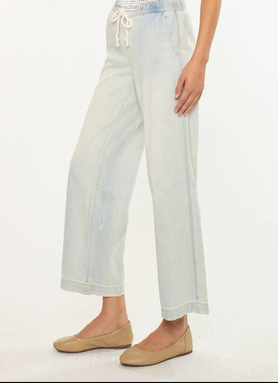 Woman wearing a white top with black trim and light blue jeans on a white background