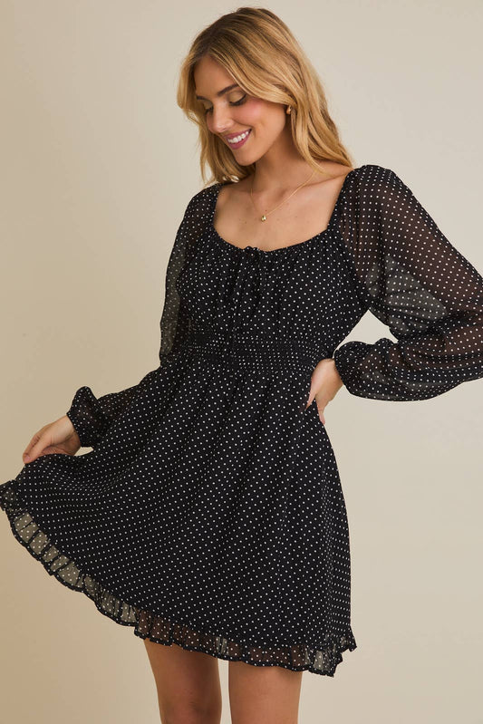 Woman wearing a black polka dot dress against a beige background