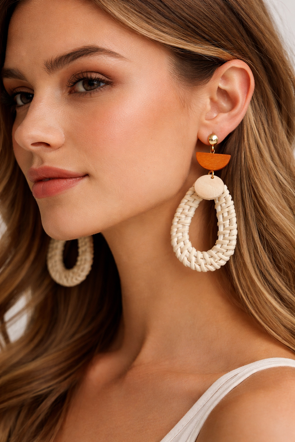Close-up of a woman wearing large beaded earrings with an orange accent.