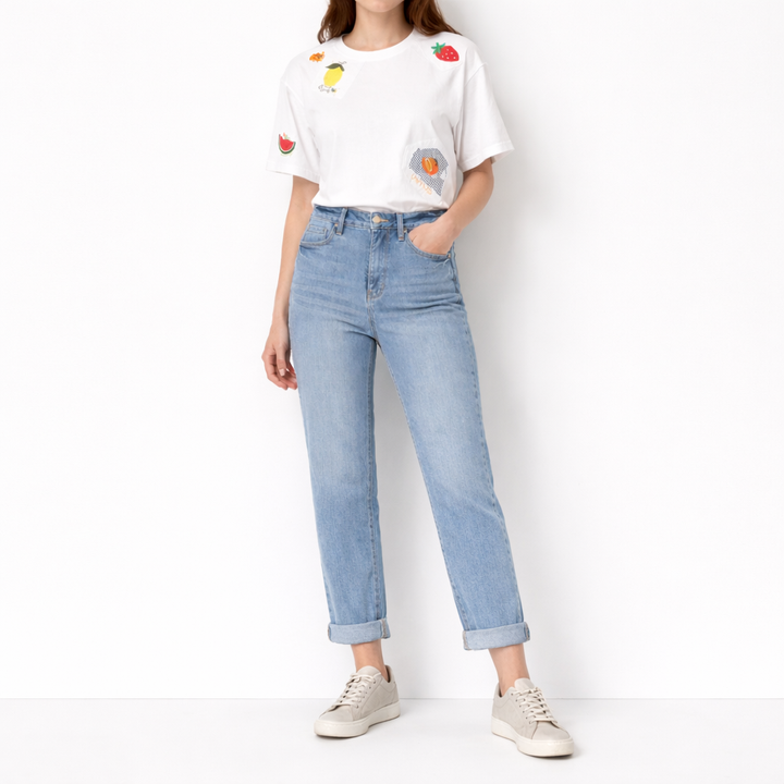 Person wearing a white t-shirt with colorful designs and light blue jeans on a white background