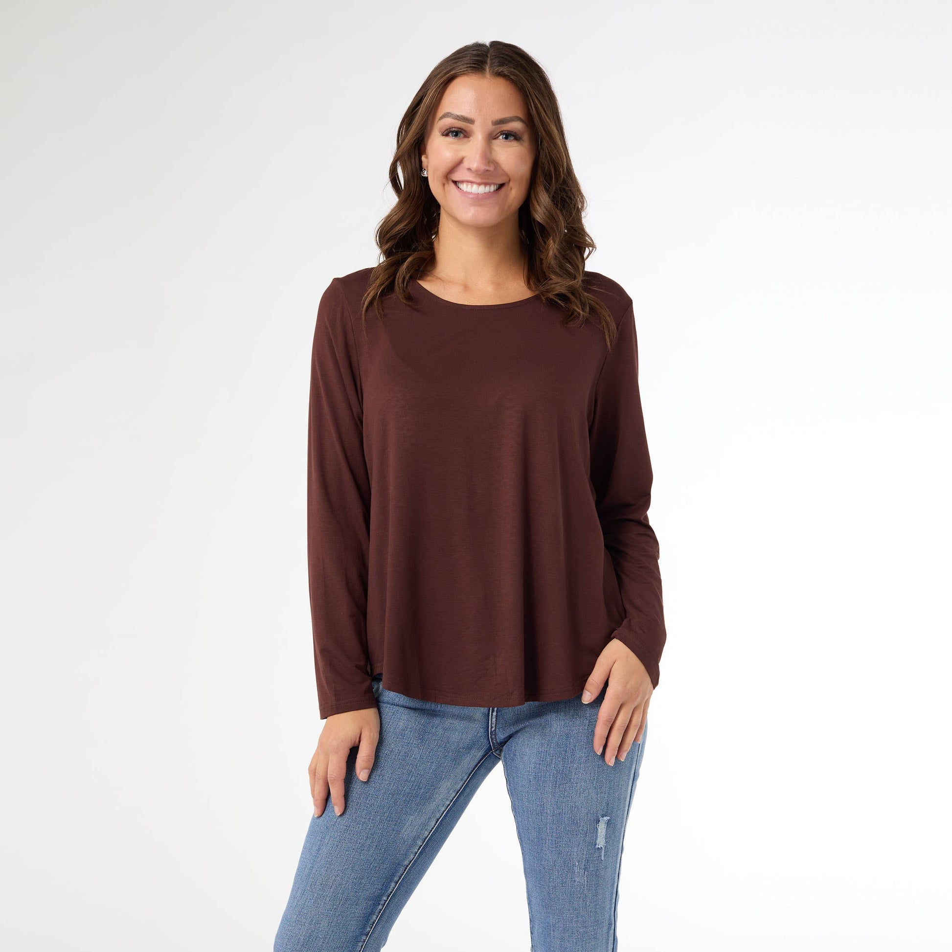 Woman wearing a brown long-sleeve top and blue jeans on a white background