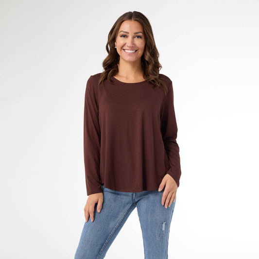 Woman wearing a brown long-sleeve top and blue jeans on a white background