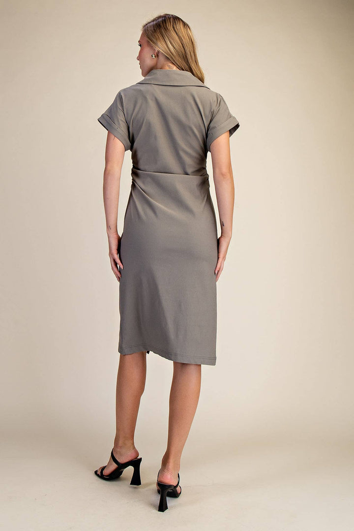 Woman wearing a fatigue dress against a beige background