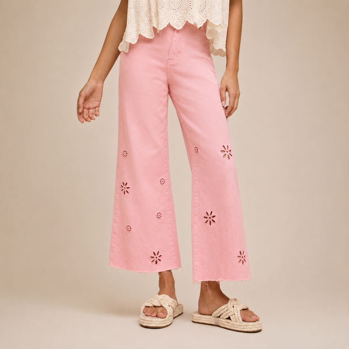 Person wearing pink pants with floral embroidery on a beige background