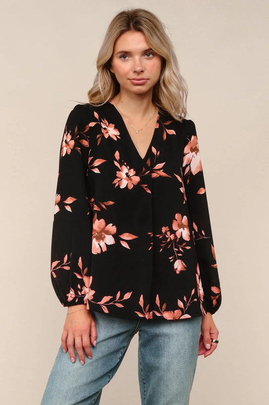 Woman wearing a black floral long-sleeve top against a beige background