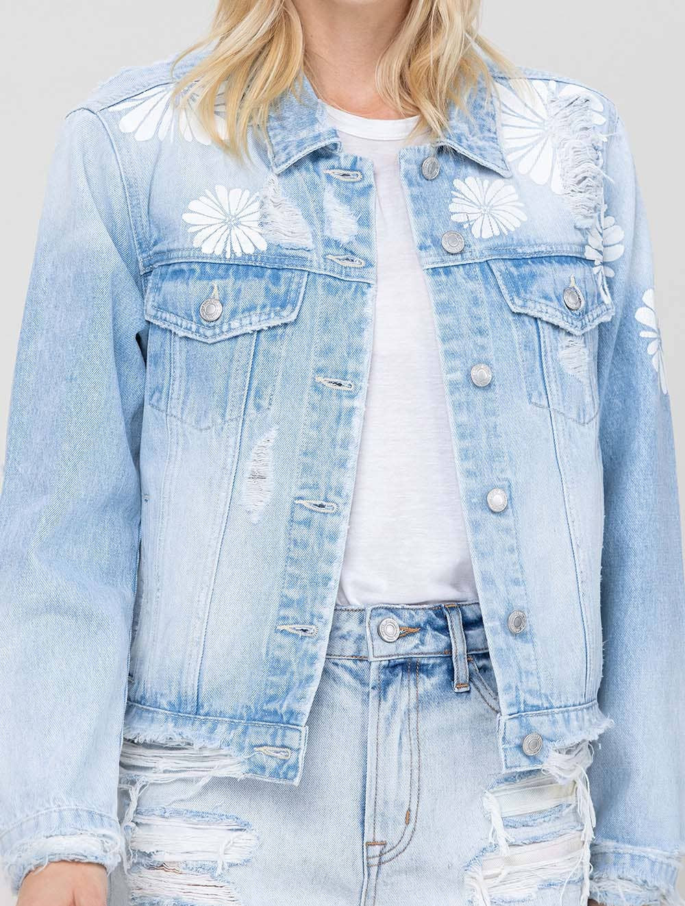 Light blue denim jacket with floral patterns worn by a person.