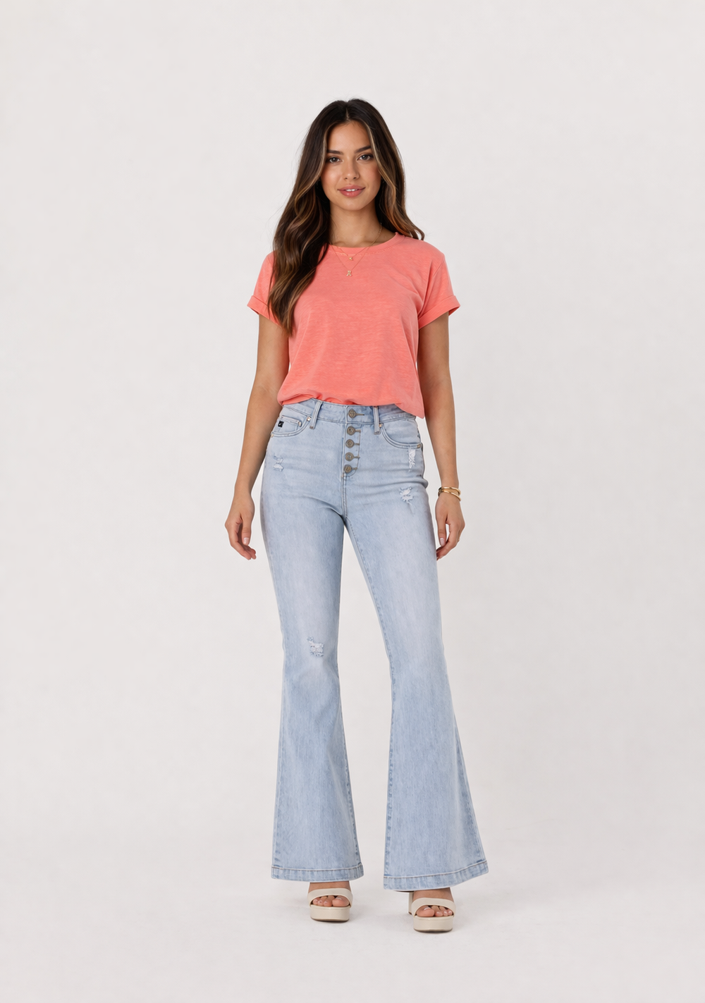 Woman wearing a coral t-shirt and light blue flared jeans on a white background