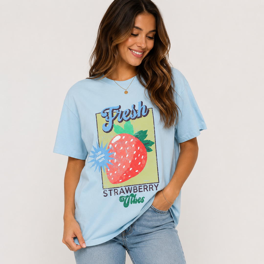 A woman wearing a light blue graphic t-shirt with a strawberry design and the words &