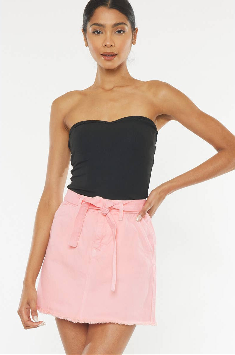 Woman wearing a black strapless top and pink skirt on a white background