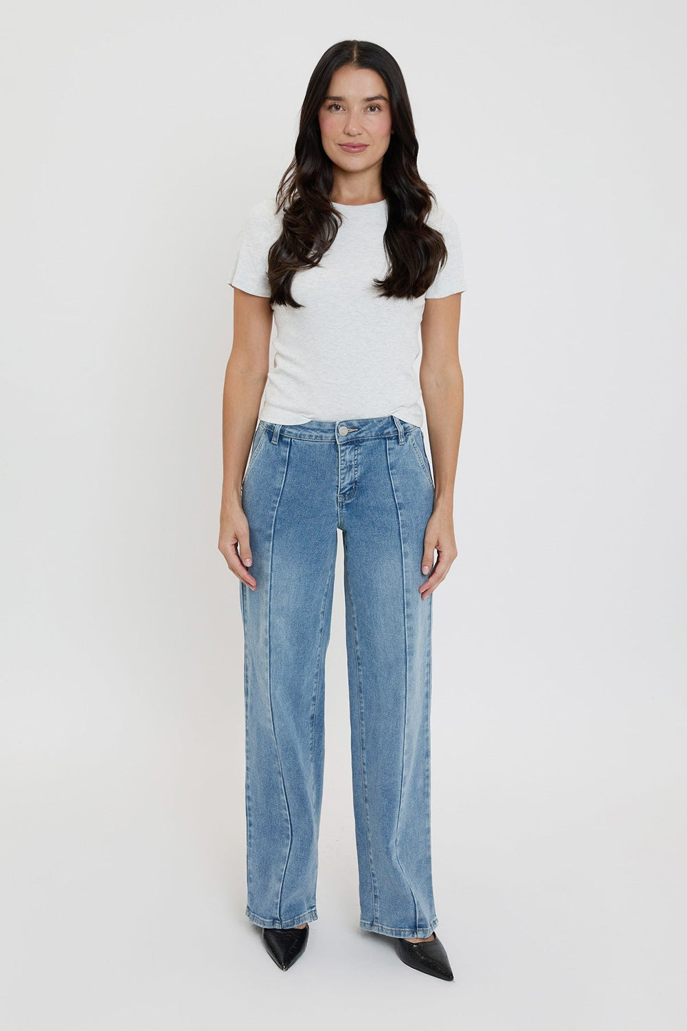 Woman wearing a white t-shirt and blue jeans on a white background