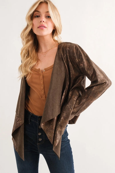 Woman wearing a brown snakeskin jacket over a mustard top and blue jeans on a white background