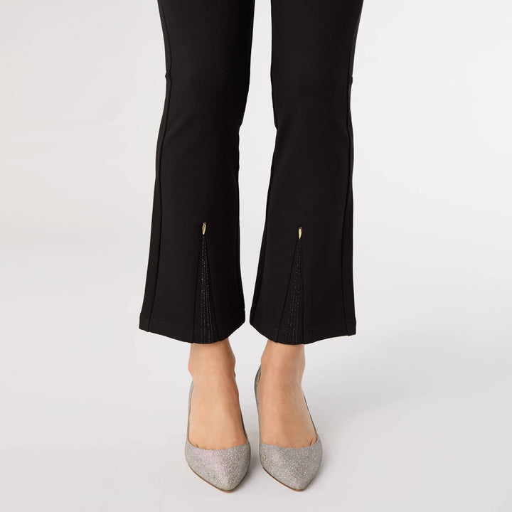 Black pants with cut-out details worn by a person on a white background