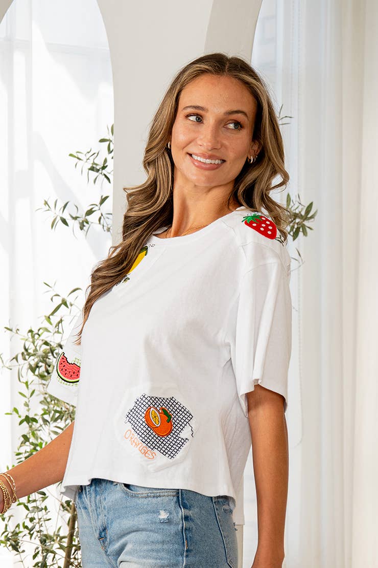 Woman wearing a white t-shirt with fruit designs in an indoor setting